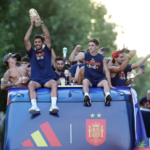 Spain's captain Rodri holds the World Cup trophy as the players parade on an open-top bus through the streets of Madrid.