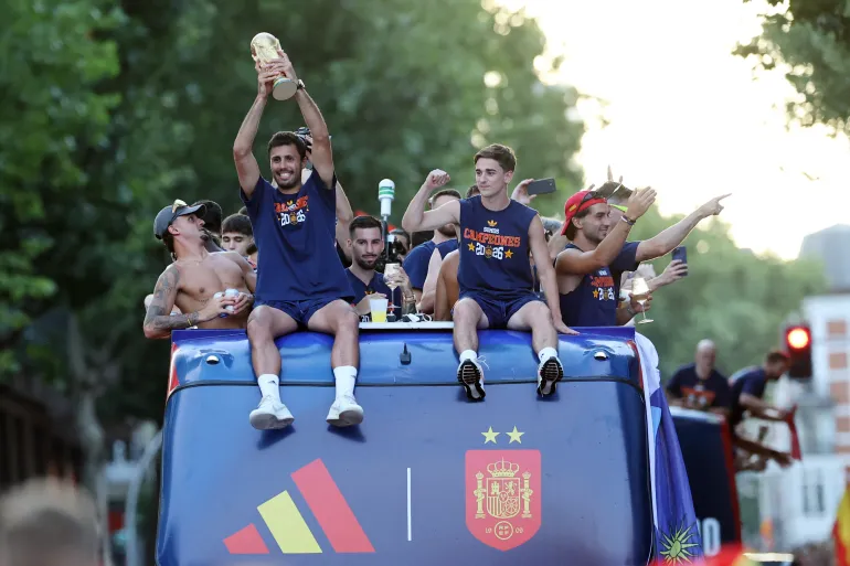 Spain's captain Rodri holds the World Cup trophy as the players parade on an open-top bus through the streets of Madrid.